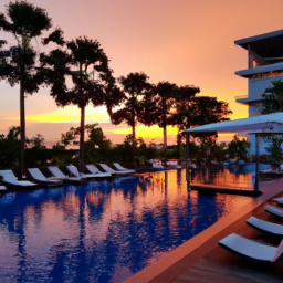 Ein Swimmingpool mit Liegestühlen und Palmen bei Sonnenuntergang.
